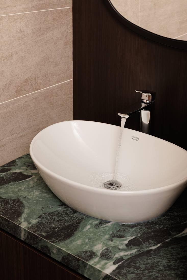 A green marble vanity with a vessel basin
